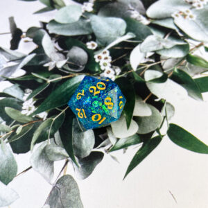 This bath-time D20 starts with a liquid core filled with blue glitter and mylar, faux pearls, and the cutest ducky glitter! The core sits inside a shell of the sparkliest, blue glitter with clear resin windows to see your duckies spin by with each roll. Finished with yellow ink, this is a fun, unique set for your collection!